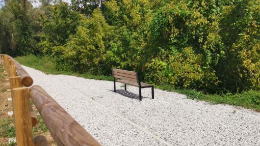 Fotografija prikazuje novo urejeno didaktično pot z leseno klopjo in leseno ograjo.