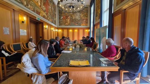 Udeleženci novinarske konference sedijo za mizo in odgovarjajo na novinarska vprašanja,