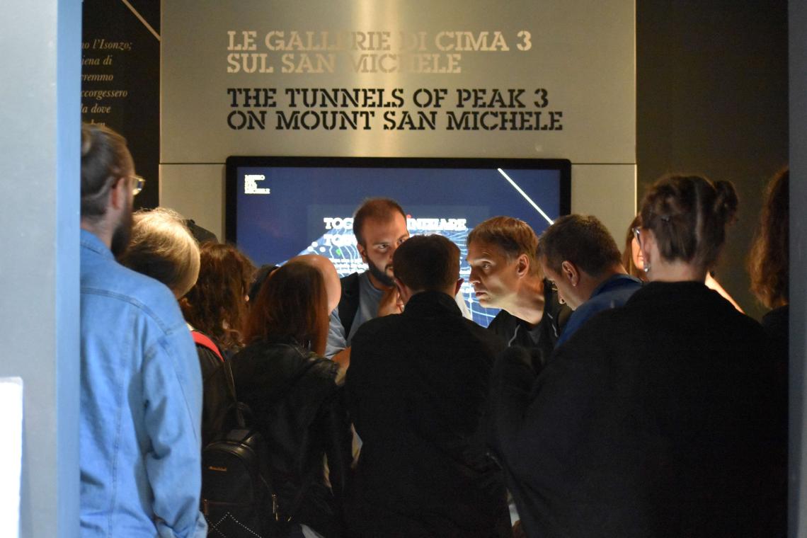 Visitors listening to guide and looking at interactive screen