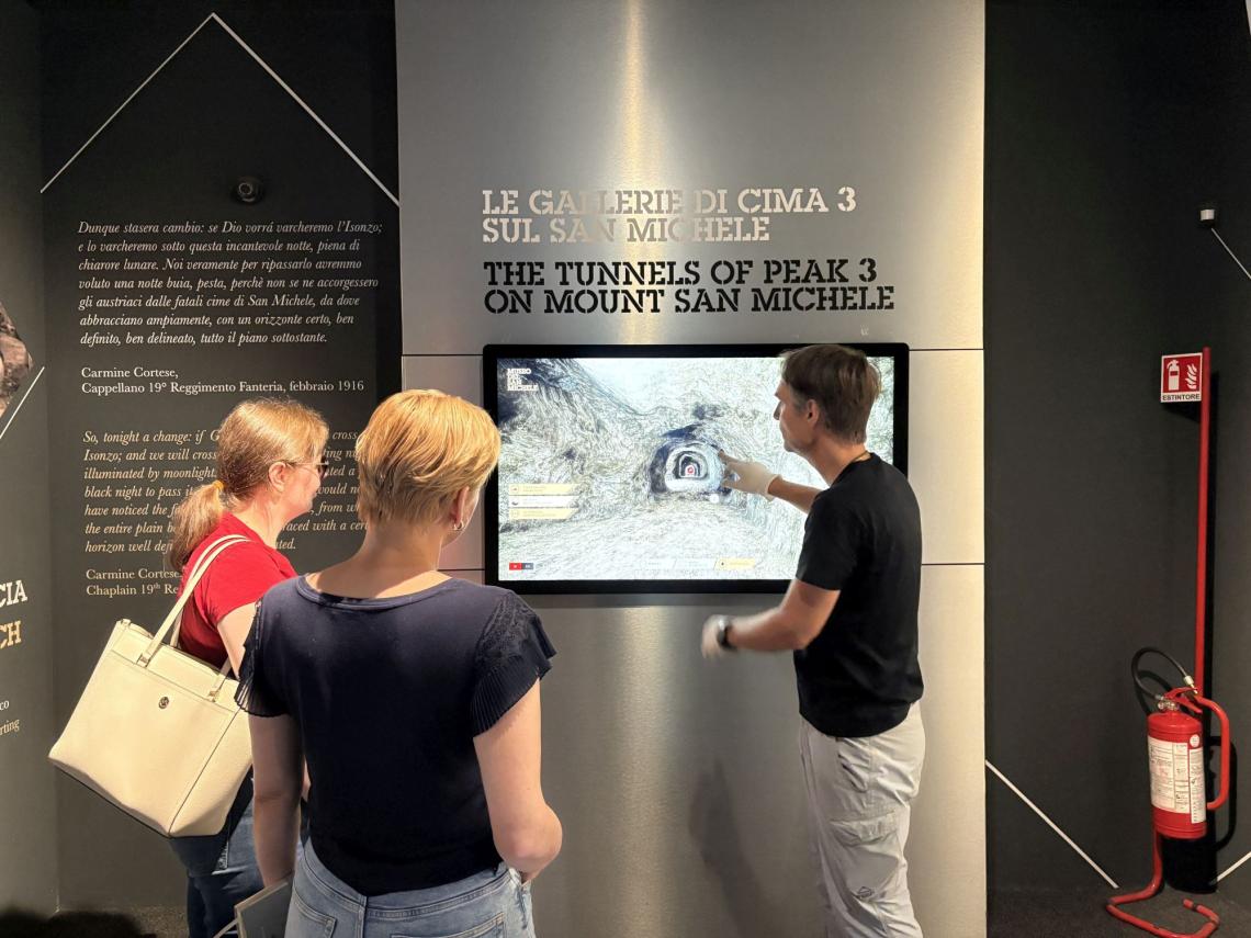 Guide showing team members museum on touchscreen monitor.